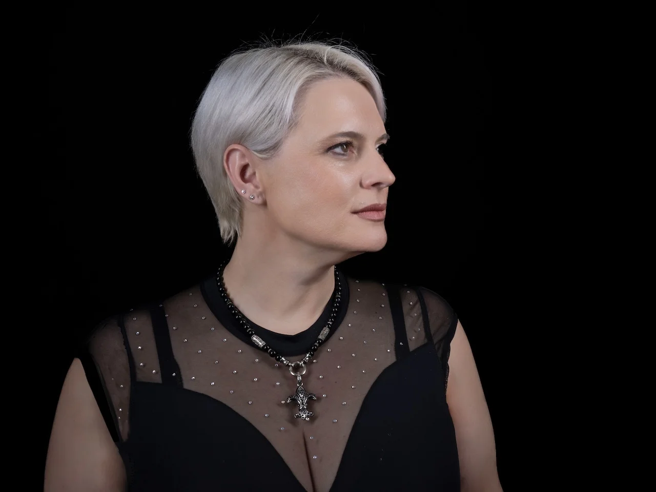Portrait von Sarah-ANN – Sängerin im schwarzen Abendkleid, nachdenklich im Profil vor schwarzem Hintergrund